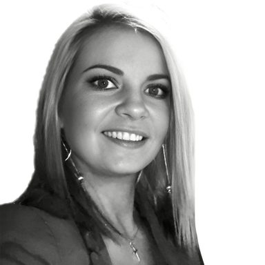 Eine lächelnde Frau mit blonden Haaren und einem blauen Blazer.