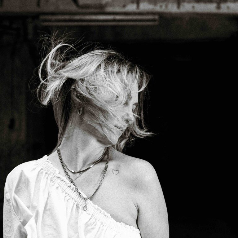 Damenhaarschnitt 2026 Frau mit wehendem Haar, schaut zur Seite, in s/w aufgenommen.